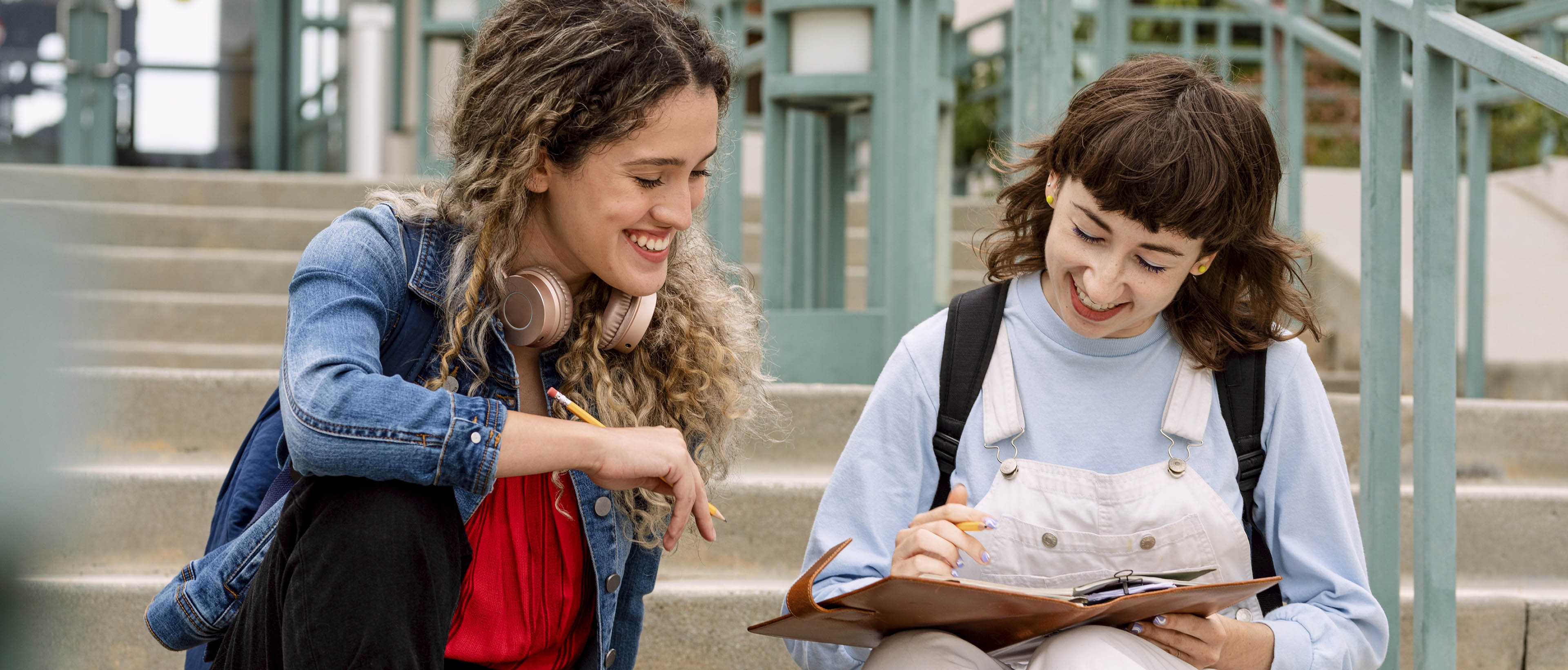 deux lycéennes font leurs devoirs assises sur un escalier