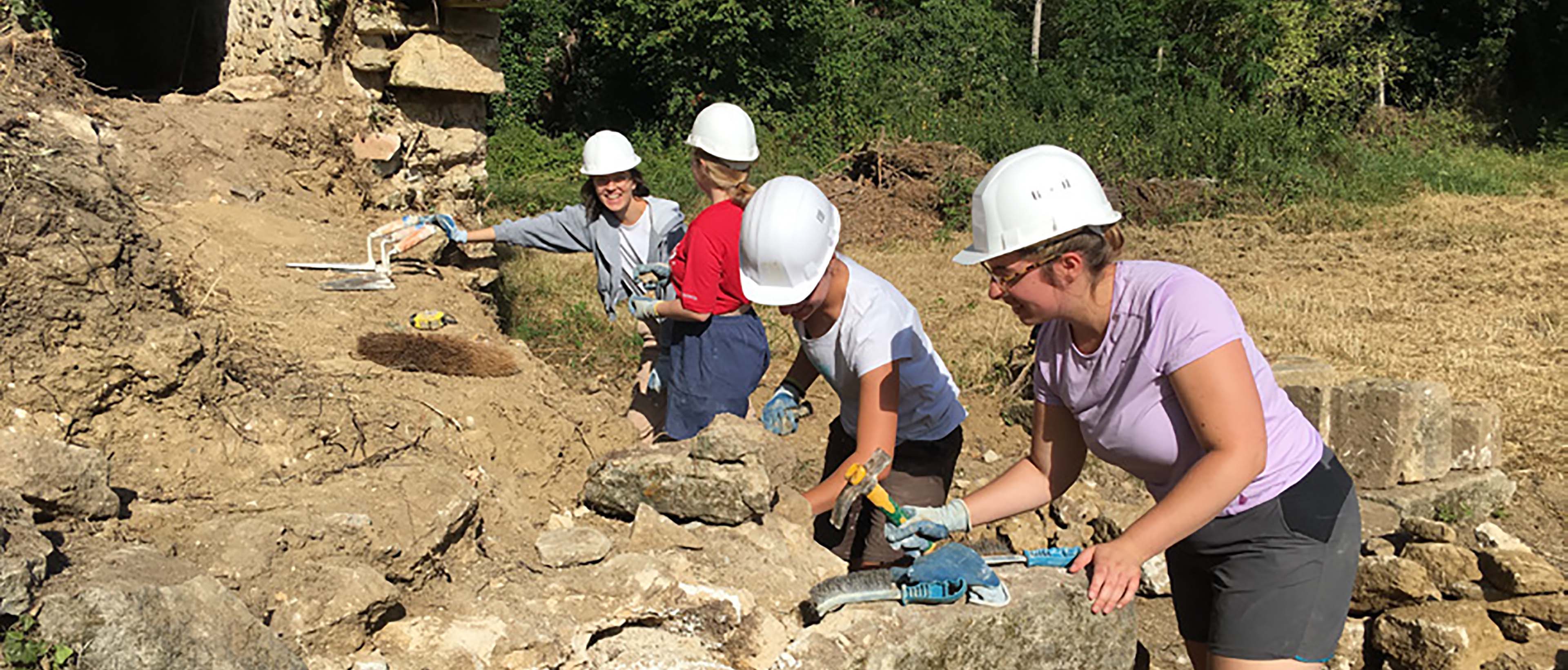 jeunes sur un chantier bénévole construisant un mur de pierre