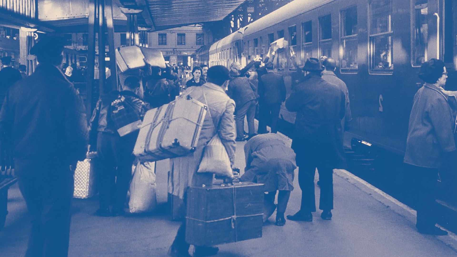 des migrants sur un quai de gare dans les années 60