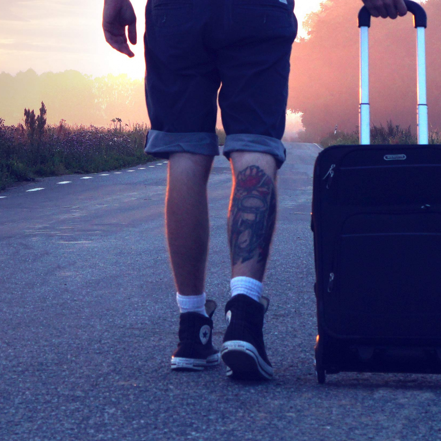 Photo d'un jeune sur le bord de la route avec sa valise