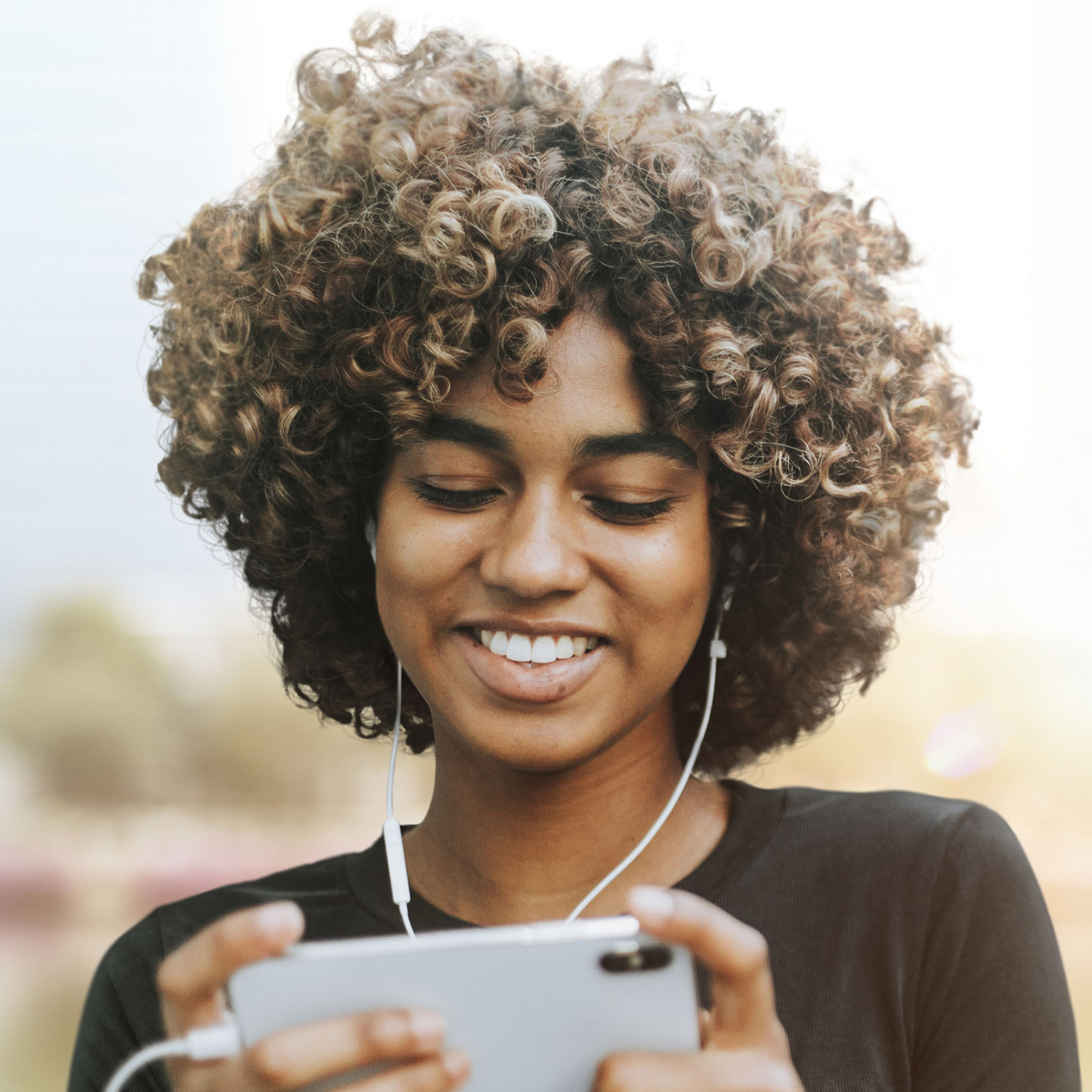 Photo d'une femme avec des écouteurs et regardant son téléphone