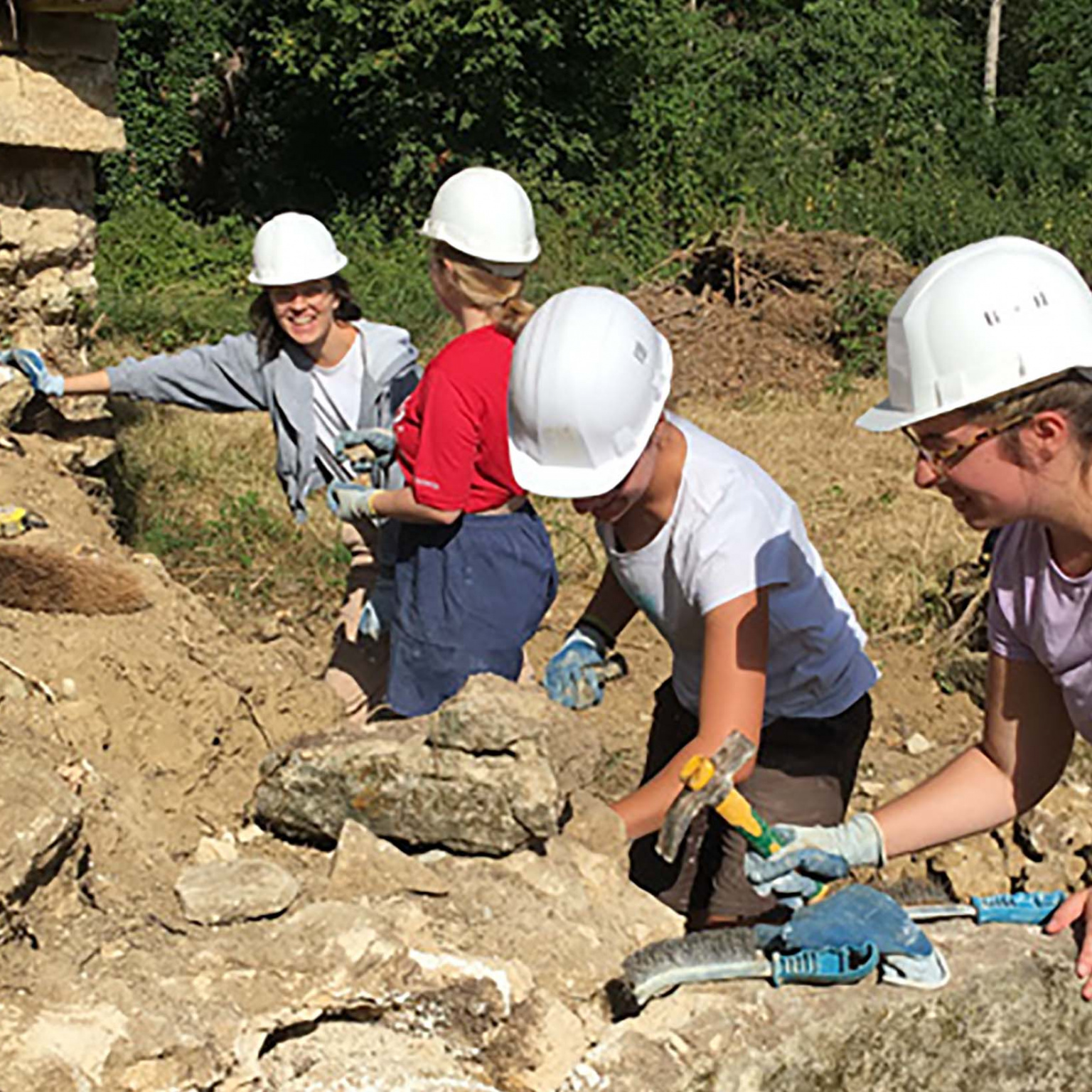 jeunes sur un chantier bénévole construisant un mur de pierre
