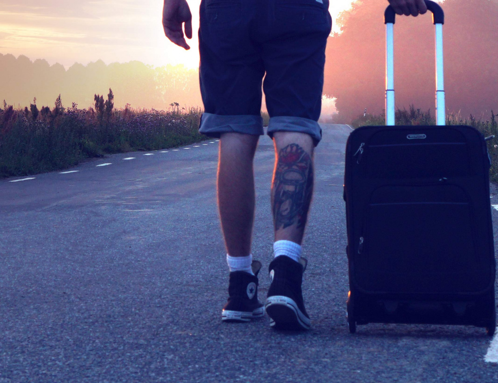 Photo d'un jeune sur le bord de la route avec sa valise