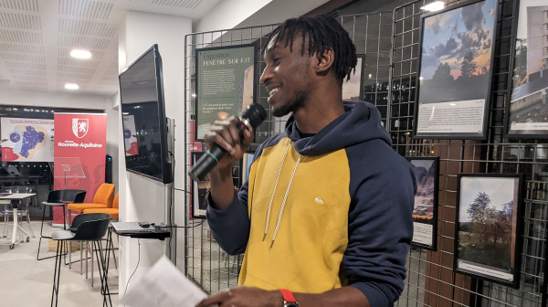 Jeune homme avec un micro devant une expo photo